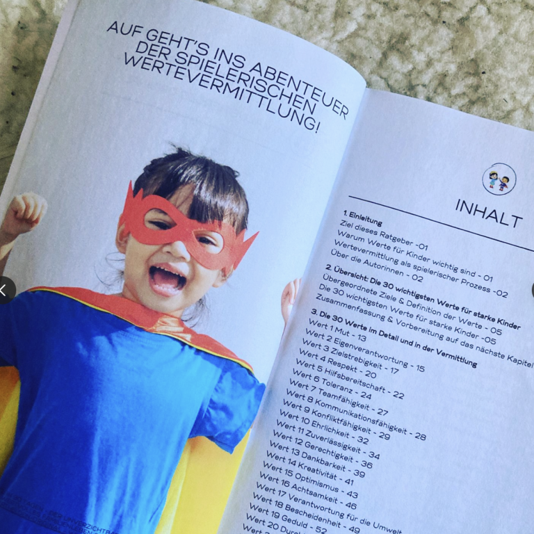 Ein kleiner Junge in einem Superhelden-Kostüm mit Umhang und Sonnenbrille.